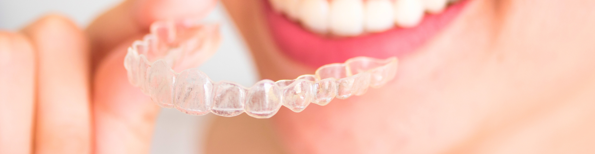 Woman placing clear aligner in her mouth.